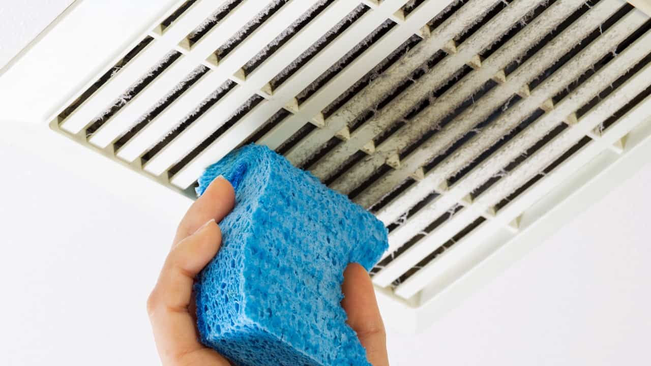 Person cleans a bathroom vent