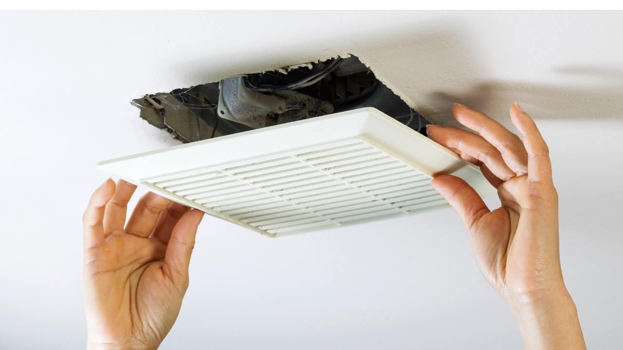 man removes bathroom fan vent cover