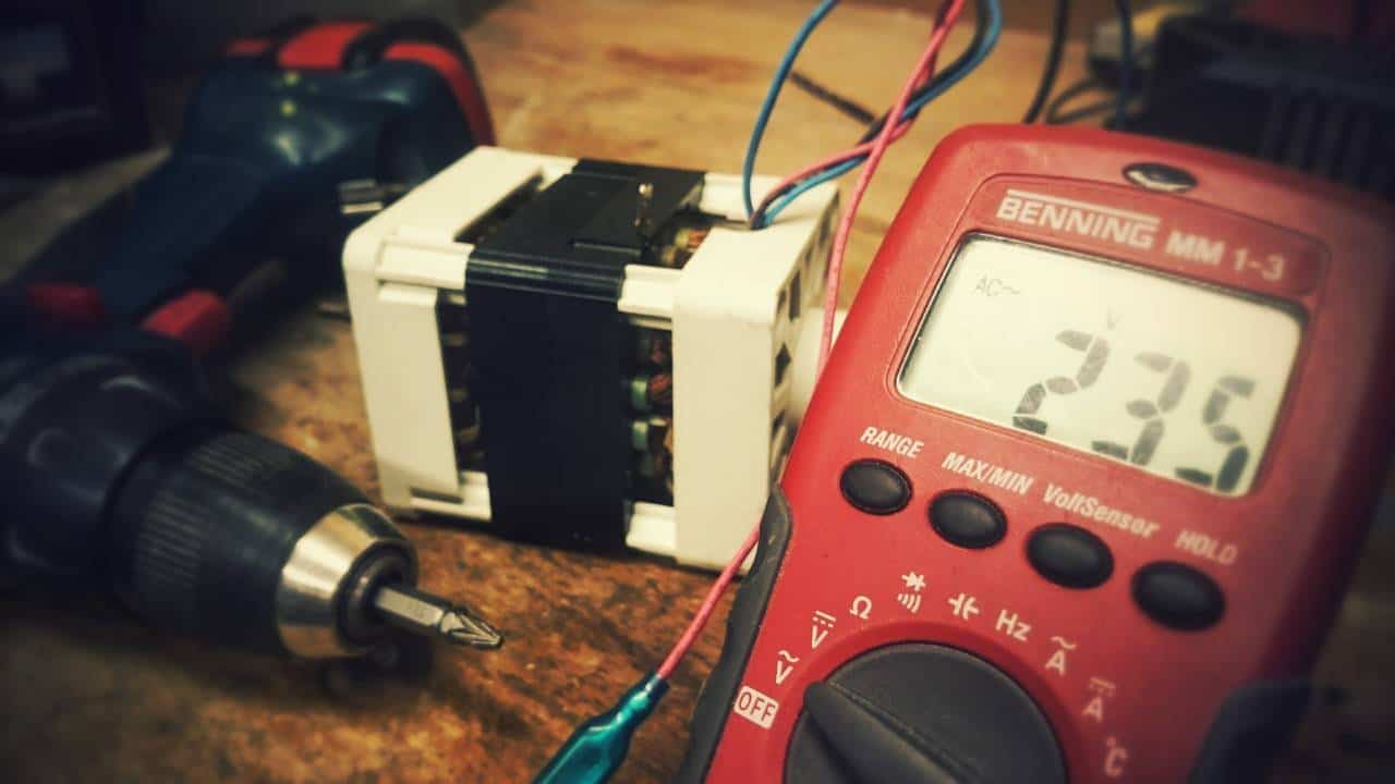 A red voltmeter and a cordless drill in a home workshop