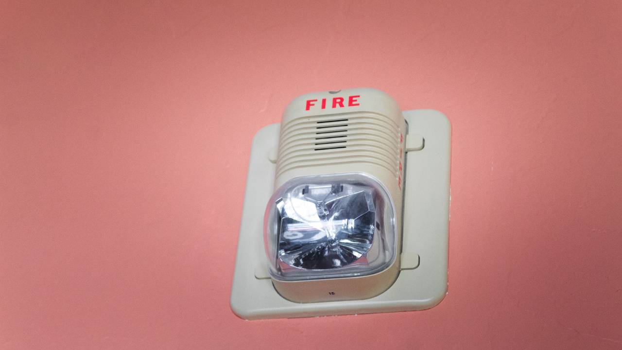 White fire alarm device on a red wall